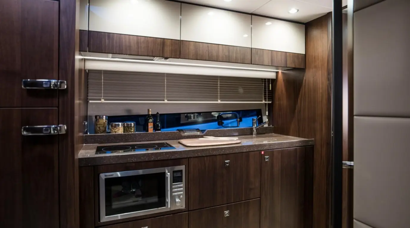 Modern kitchen with wooden cabinetry, microwave, glass cooktop, and countertop, featuring a window with blinds.